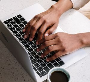Zwei Hände liegen auf der Tastatur eines Computers und beginnen gleich zu tippen.