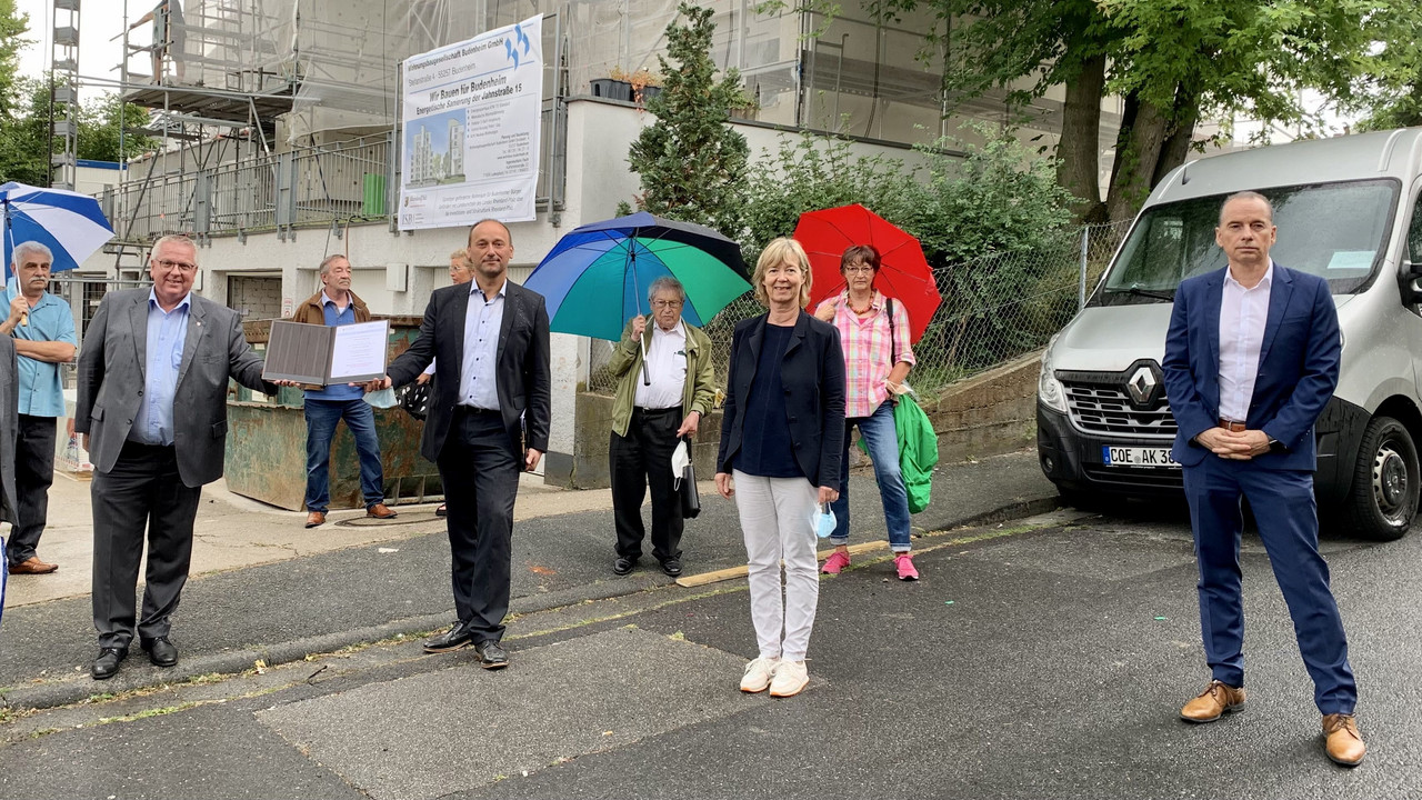 Viele Menschen stehen auf der Straße vor einer Baustelle. 